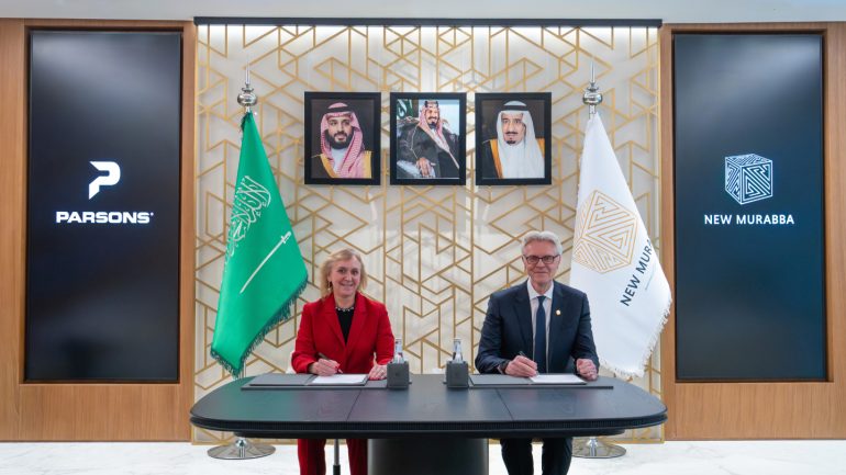 مايكل دايك، الرئيس التنفيذي لشركة نيومورابا، يوقع الاتفاقية مع كاري سميث، رئيس مجلس الإدارة والرئيس التنفيذي لشركة بارسونز.