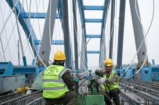 西渝高铁康渝段跨营达高速公路大桥上工人正在调试机器。