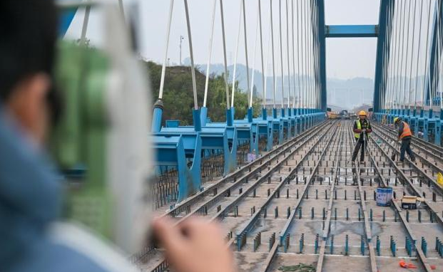 测量人员正在西渝高铁康渝段跨营达高速公路大桥上开展测量作业。