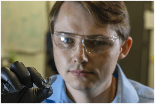 辐照工程组的辐照设计工程师尼克·罗素手持一块氧化铝形成奥氏体钢样品，这种材料有望用于铅冷快堆。