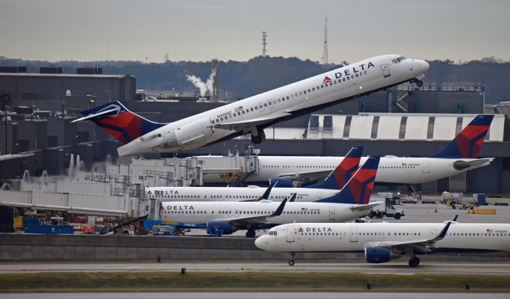 Delta 717 taking off with many Delta aircraft parked in the background