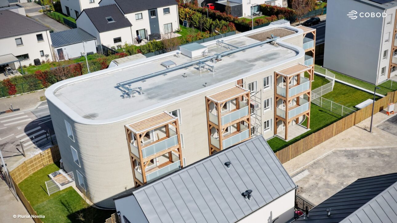 ViliaSprint²的街道视角,这是欧洲最大的3D打印多户住宅楼,位于法国贝赞讷。现场用COBOD BOD2打印机打印的曲线混凝土结构,搭配木质阳台。图片:Cobod.com