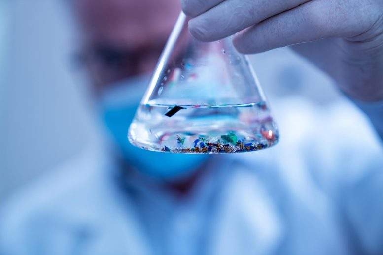 科学家检查实验室烧瓶中的小塑料颗粒