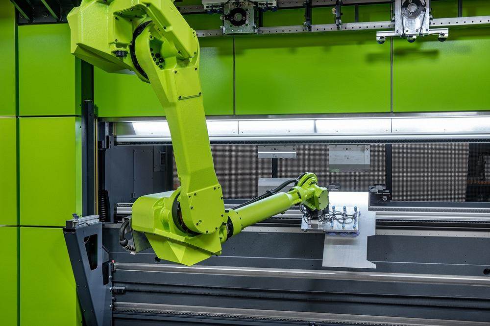 Un robot introduce una lámina metálica en una plegadora.