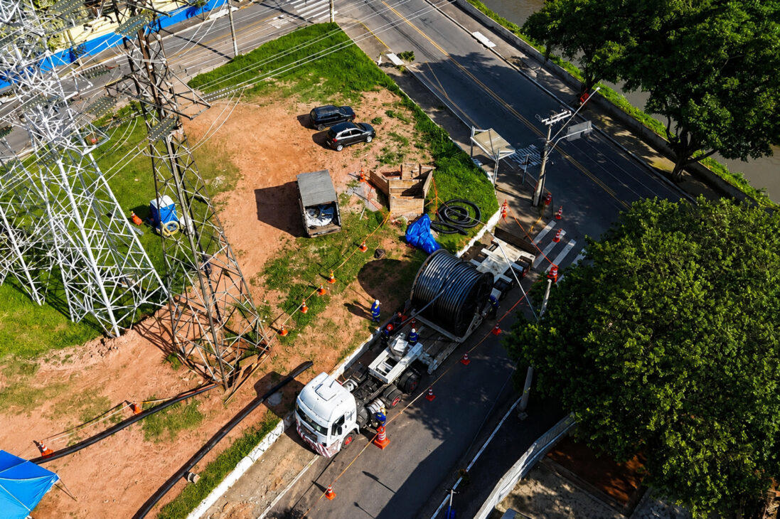 Em área urbana de São Paulo, equipe de obra instala cabos de transmissão subterrâneos ao lado de torres de transmissão, como parte do Projeto Riacho Grande.