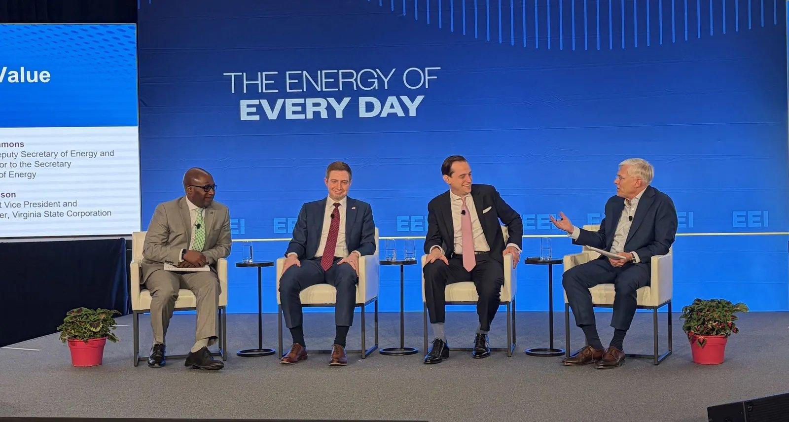 Vier Personen stehen auf einer Bühne, der Hintergrundbildschirm zeigt „Tägliche Energie“