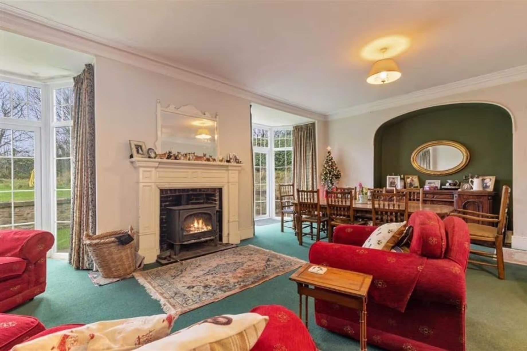 Le salon-salle à manger est un autre espace confortable, mais la plupart des gens estimeraient probablement que son intérieur nécessite une mise à jour, avec un canapé rouge, une moquette verte et une table et des chaises en bois