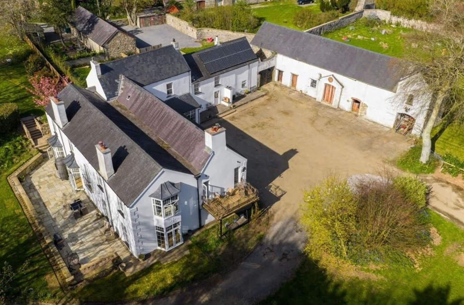Vue aérienne révélant l'ampleur de la maison principale, des granges annexes et des hébergements supplémentaires. Les dépendances rénovées expliquent pourquoi l'agence indique que ce site historique offre 12 chambres. Manoir Johnston Hall près de Haverfordwest, mis en vente pour 1,85 million de livres sterling par Fine & Country West Wales (Aberystwyth)