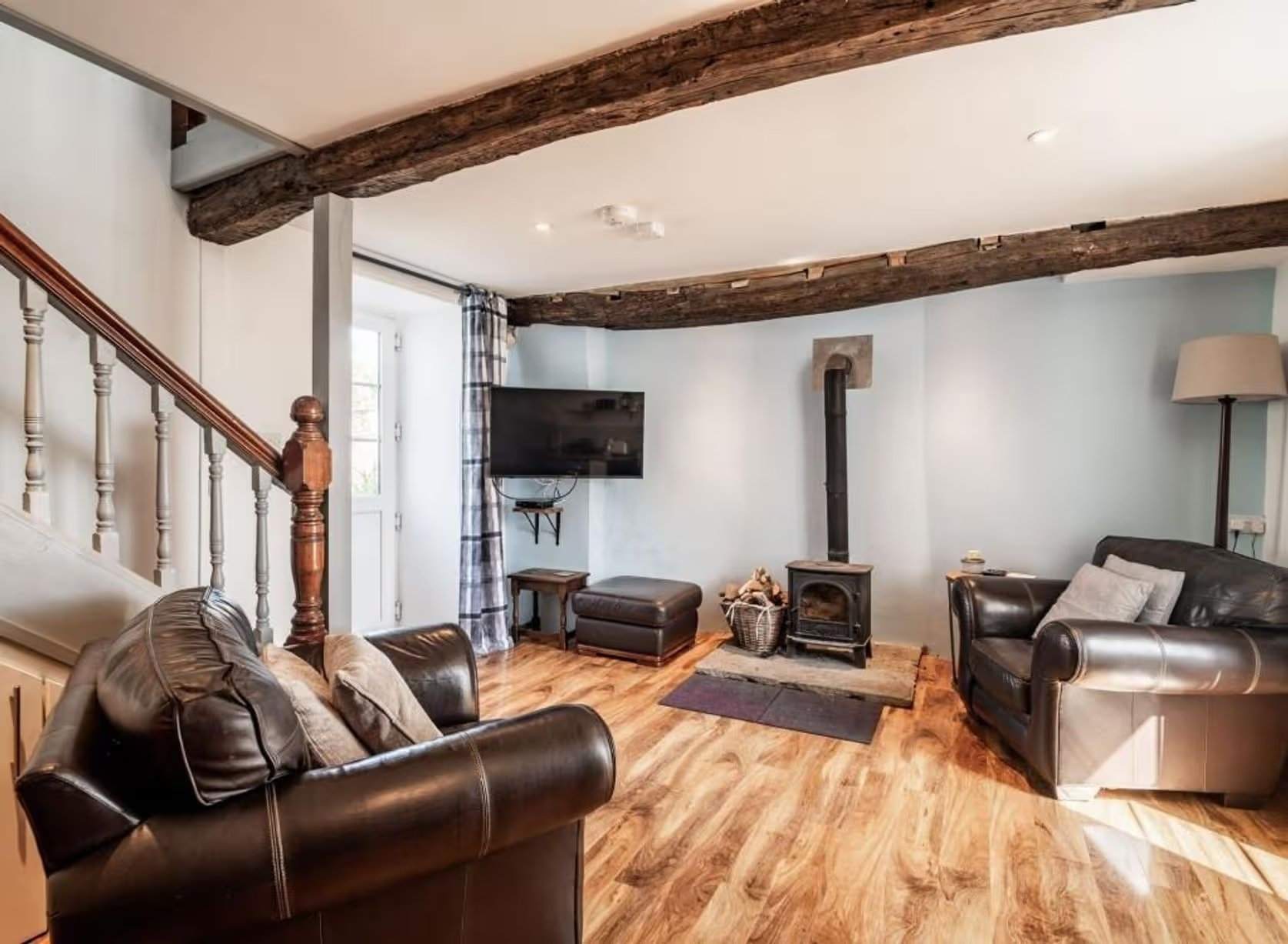 Intérieur de l'un des cottages rénovés, avec poutres apparentes au plafond, parquet et poêle à bois. Manoir Johnston Hall près de Haverfordwest, mis en vente pour 1,85 million de livres sterling par Fine & Country West Wales (Aberystwyth)