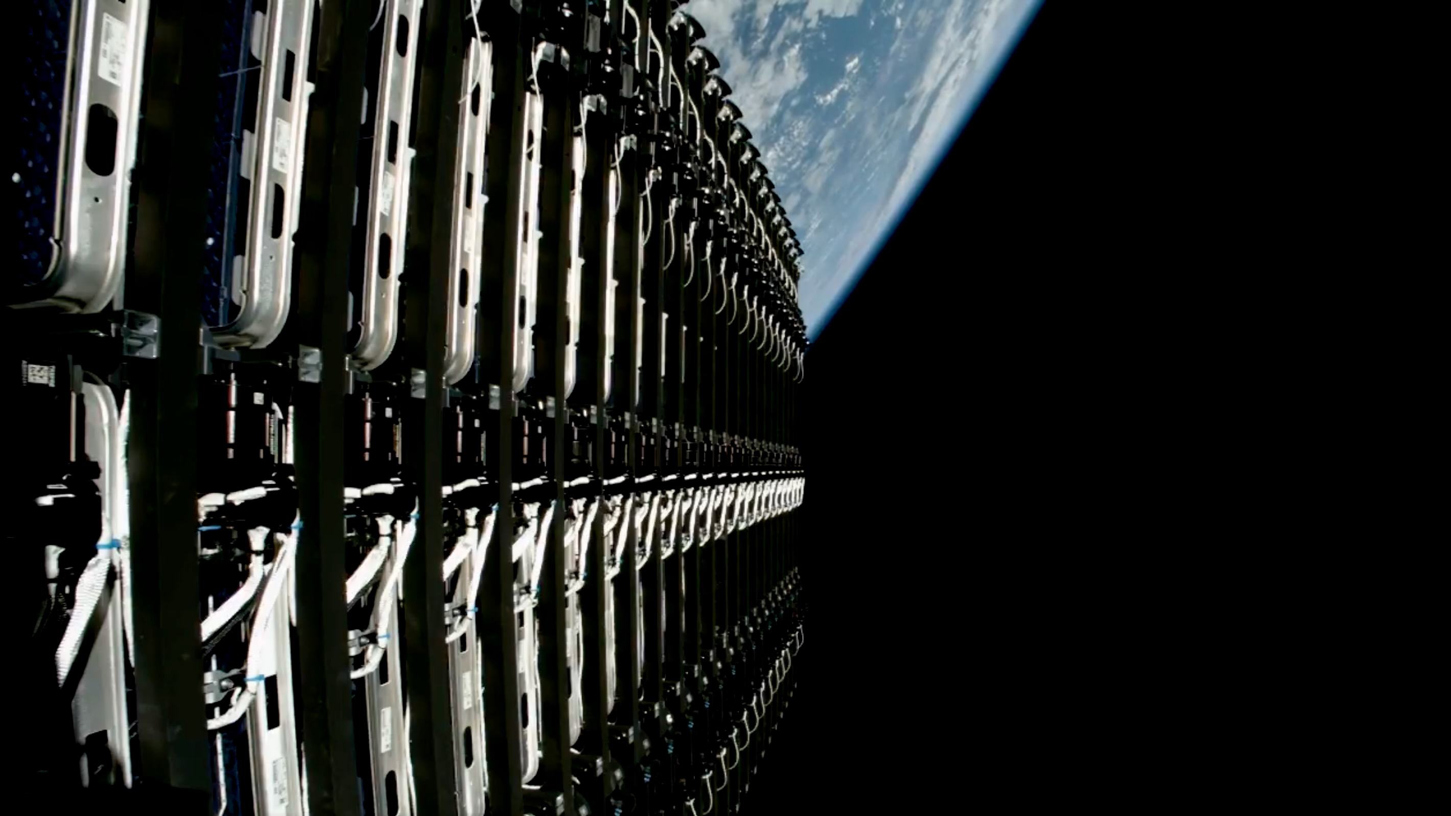 Close-up view of 24 flat Starlink satellites before deployment in space, with Earth in the background