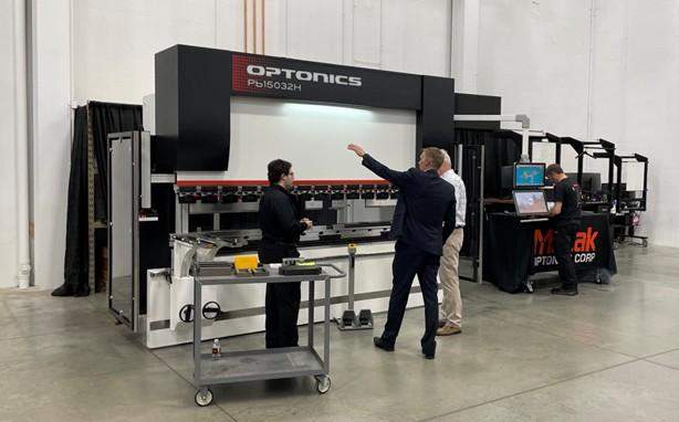 Three people standing in front of a press brake