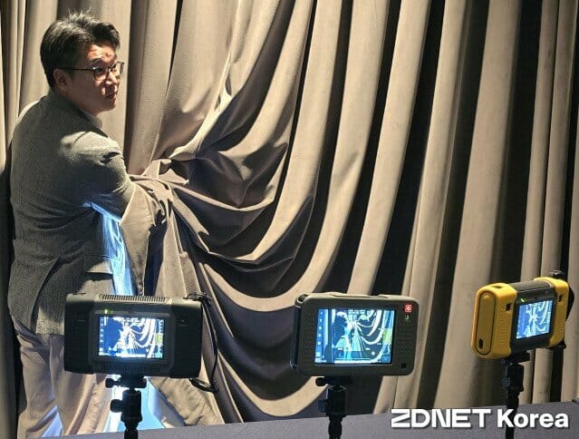 SM Instrument a démontré les performances du « BATCAM-3.0 » (au centre du produit) lors du « Forum sur l'intelligence industrielle » organisé le 18 pour célébrer son 20e anniversaire. Même en vaporisant légèrement un spray derrière un rideau, le « BATCAM » peut le détecter avec précision.