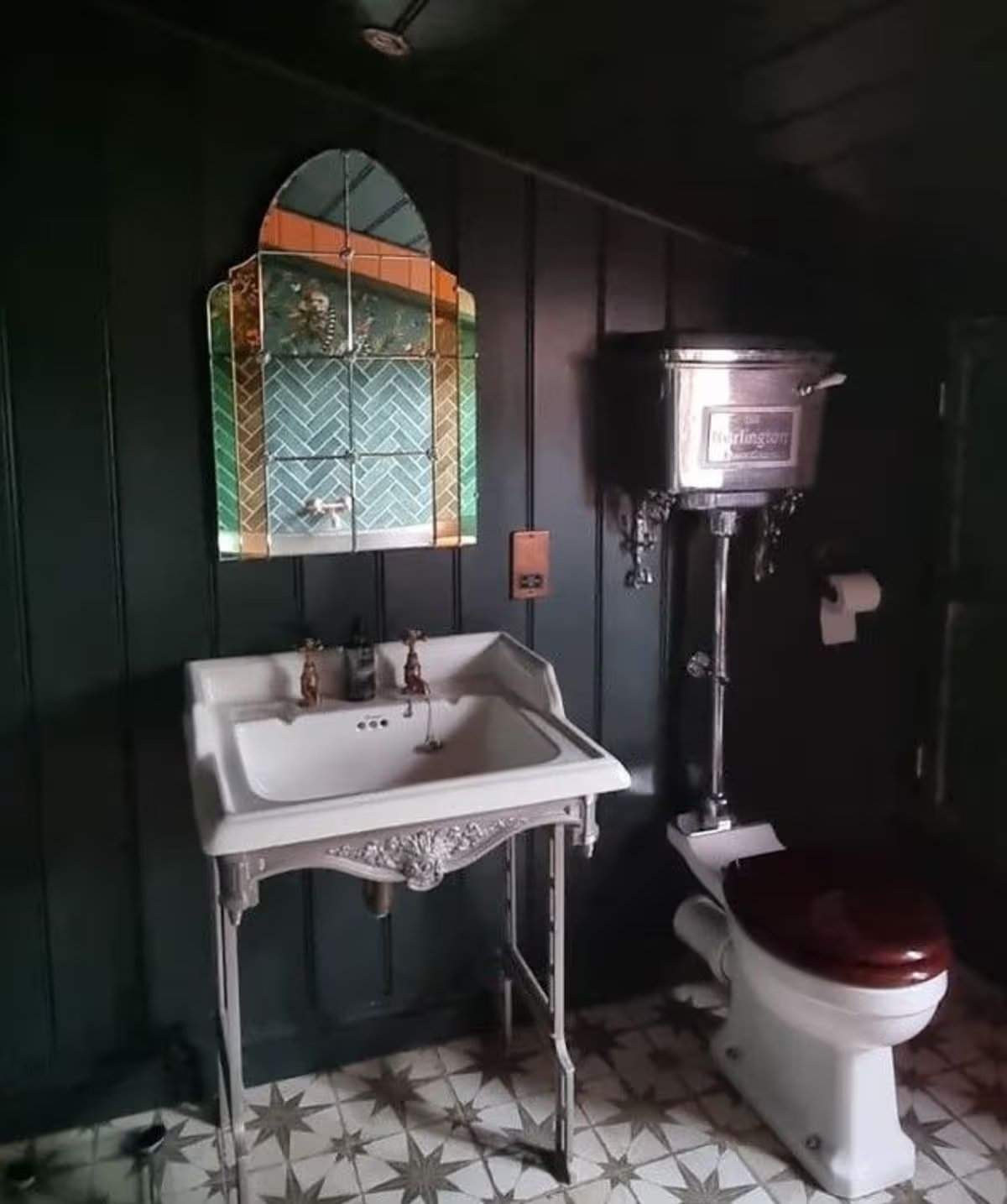 Das Badezimmer verfügt über eine freistehende Zinkbadewanne, eine begehbare Dusche mit dunkelgrünen Fliesen, eine traditionelle Toilette und ein Waschbecken sowie eine Holzvertäfelung in Schwarz, Grau und zartem Pfirsich. Jane Beck Welsh Blankets in ihrem renovierten Zuhause in der Nähe von Tregaron, Ceredigion. Die Renovierung dauerte 29 Jahre, und sie hatte anfangs nur 23 Pfund in der Tasche.
