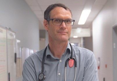 Paul Young steht in einem Krankenhausflur, ein Stethoskop hängt um seinen Hals.