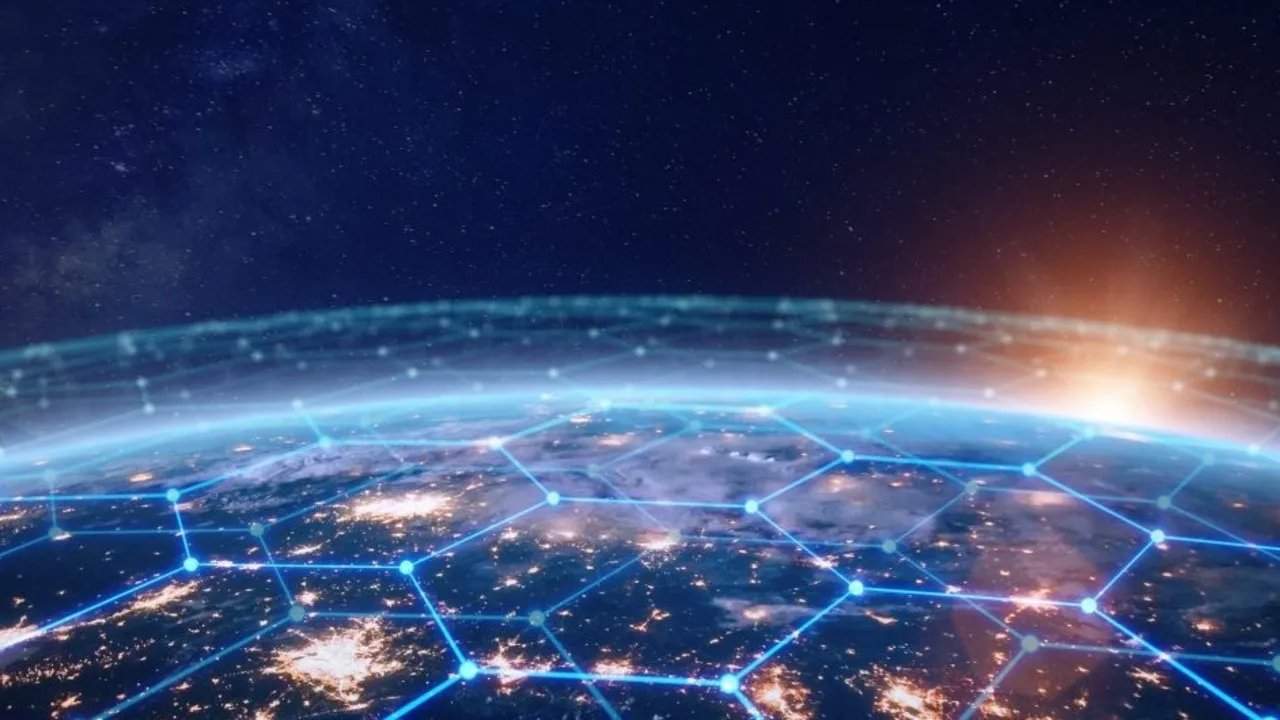 Вид на Землю из космоса, покрытую светящейся сеткой из синих шестиугольников, на горизонте восходит солнце на фоне звездного неба.