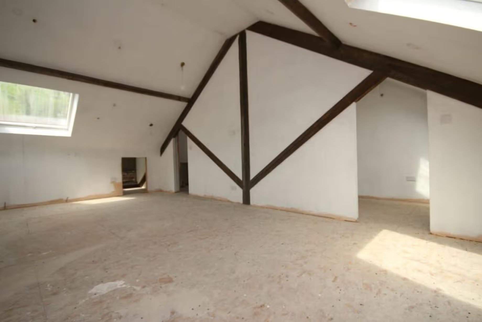 Pièce vide au dernier étage, murs blancs, poutres en bois d'époque apparentes, rappelant aux visiteurs ou aux enchérisseurs potentiels que le bâtiment est non seulement spacieux mais aussi plein de caractère, dans le Workmen's Institute de Brynsteedle partiellement rénové, mis aux enchères par Seel & Co, prix de départ 195 000 £, permis de construire pour transformation en logements obtenu