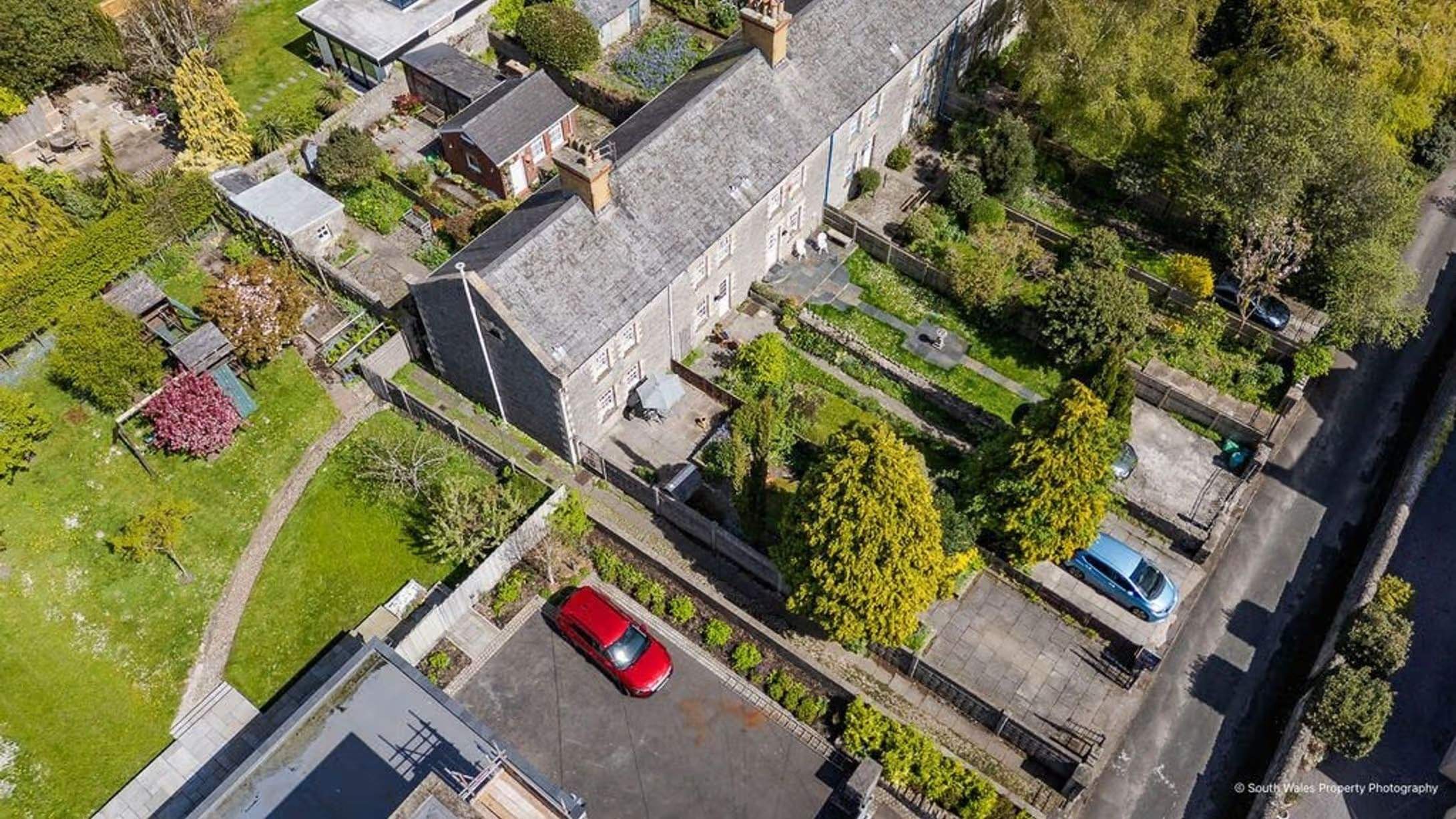 Aerial photograph of the coastguard cottage terrace, showing off-street parking, garden size, and the lane leading to this row of historic homes