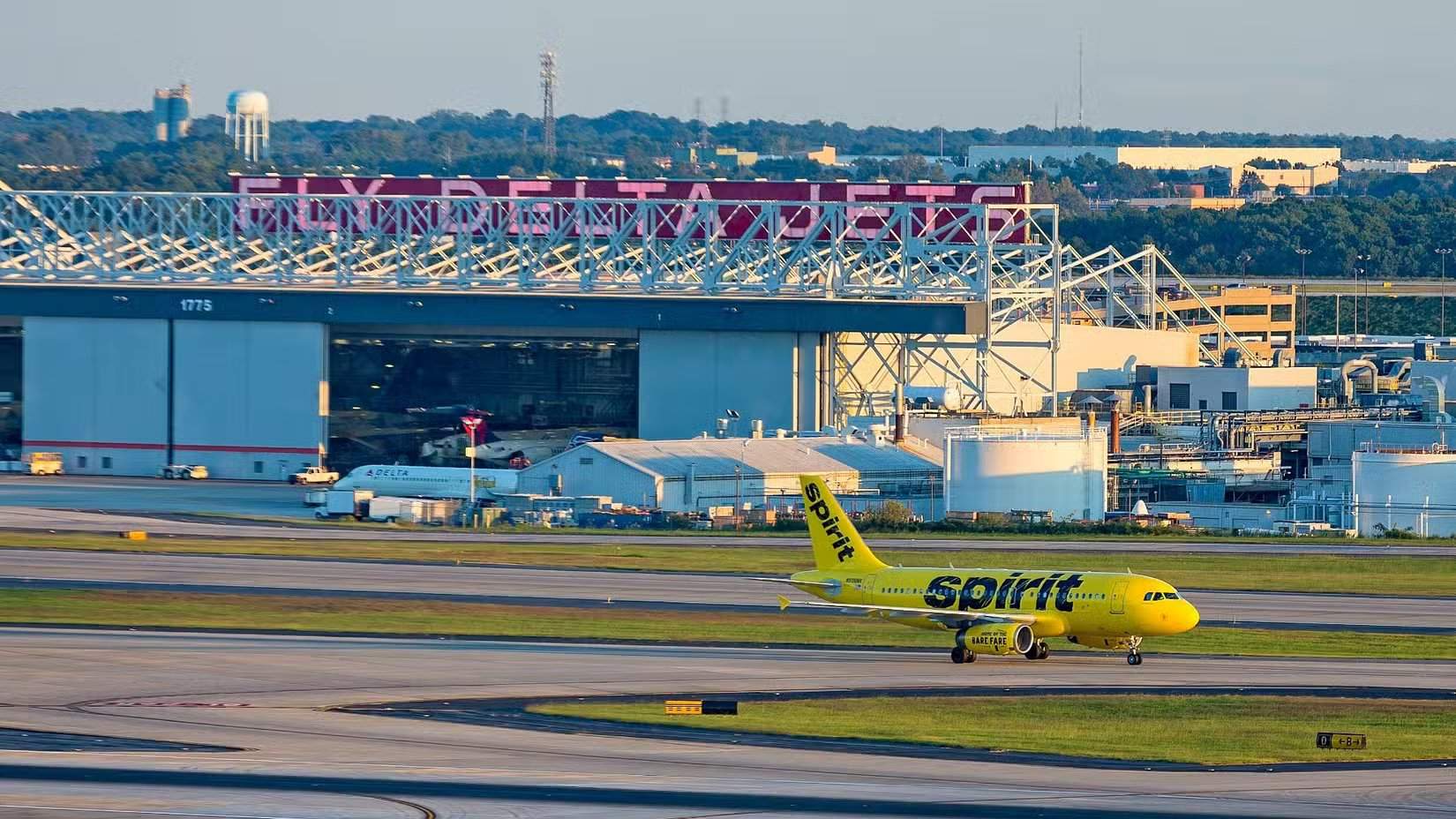 Самолёт Spirit Airlines рулит мимо ангара Delta в ATL