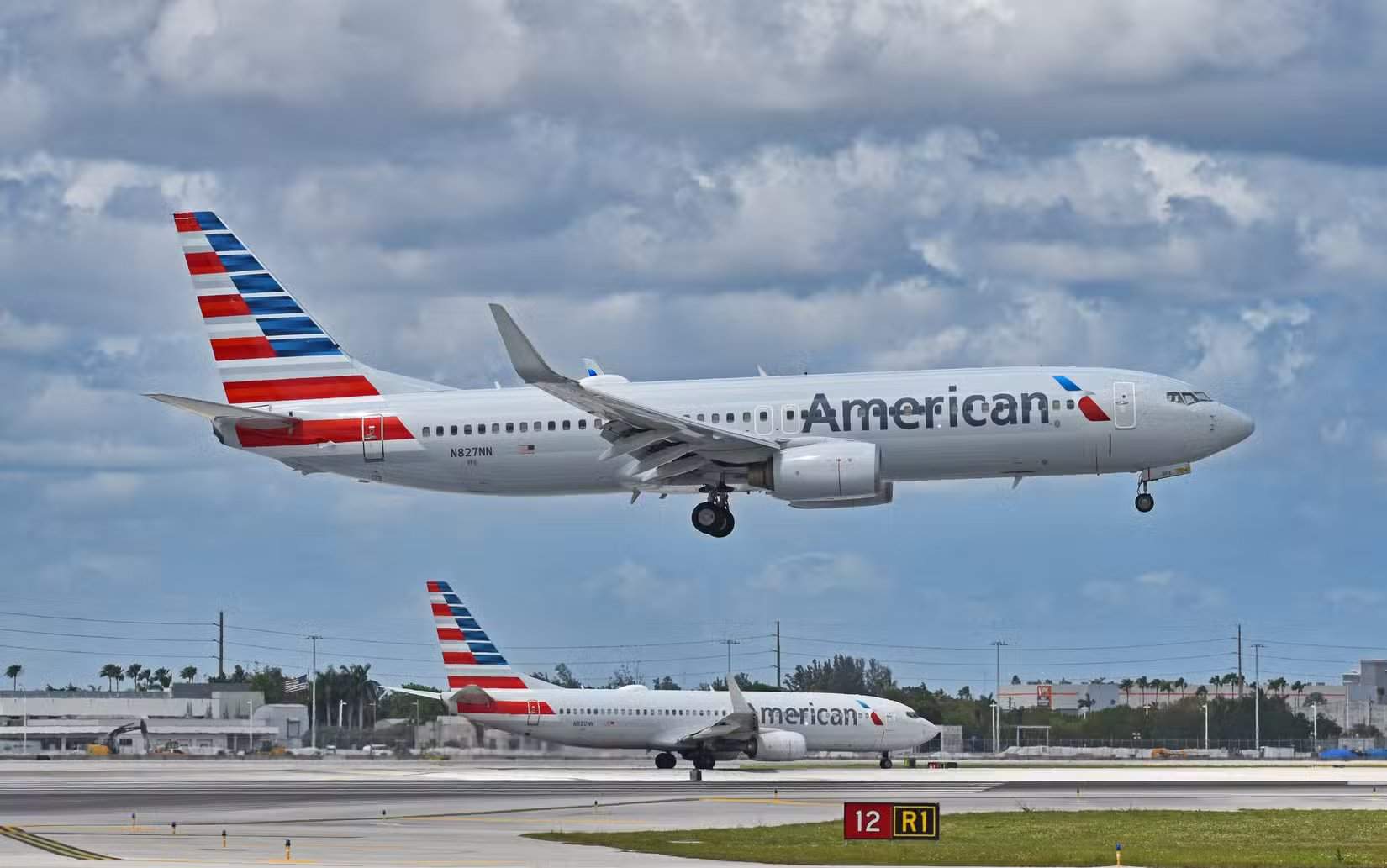 Two American Airlines (AA) Boeing 737-800 airplanes, N880NN and N827NN, departing and arriving at Miami International Airport (MIA) on a stormy day.