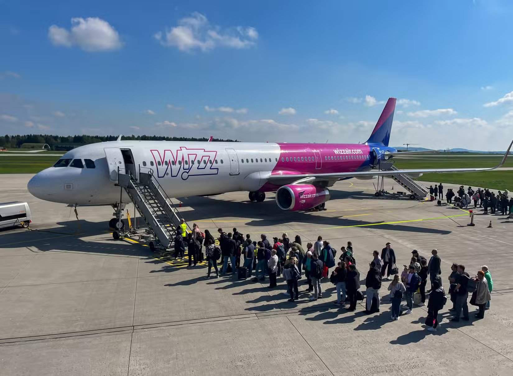 Passagiere warten auf dem Vorfeld auf ein Wizz Air-Flugzeug
