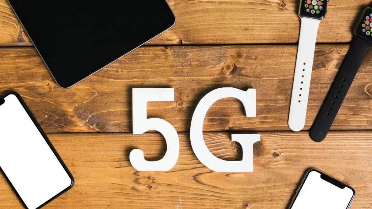 Two mobile phones, a tablet, and two smartwatches displaying a 5G logo on a table