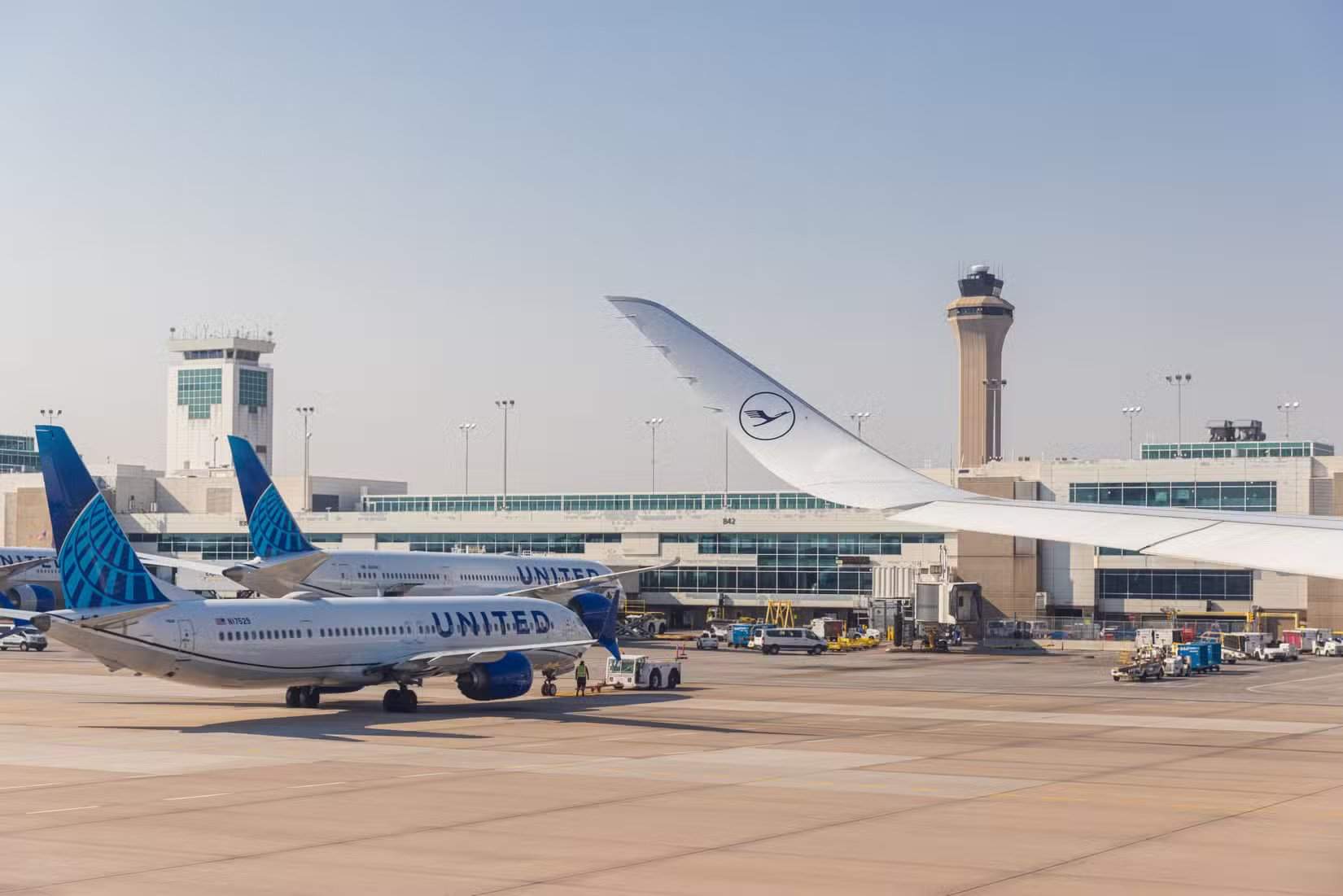 A United Airlines aircraft parked at Denver International Airport, with a wing and Lufthansa logo in the foreground