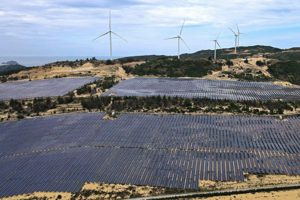 Champ de panneaux solaires à côté d'éoliennes