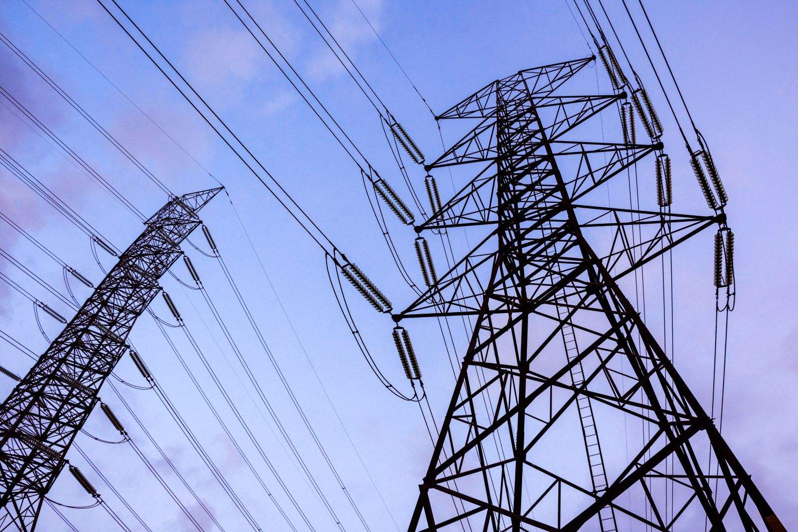 Poteaux électriques menant à une campagne sous un ciel sombre, photographiés par Nuttapon via Adobe Stock