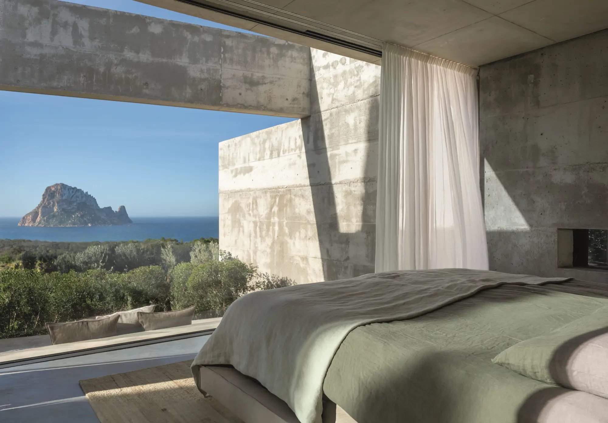 Schlafzimmer mit Beton, grüner Bettwäsche und Meerblick
